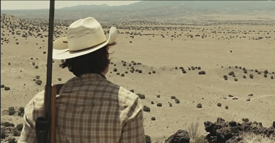 A man in a cowboy hat looks over the plains